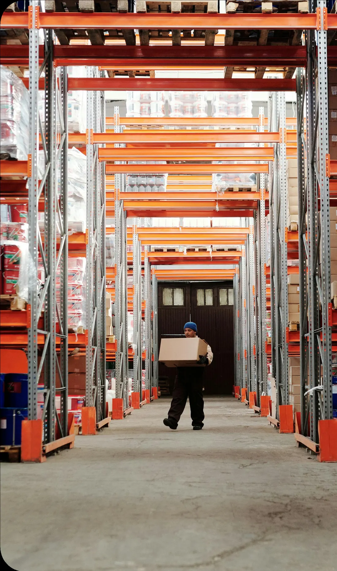 Worker walking between tall racking aisles in a distribution warehouse